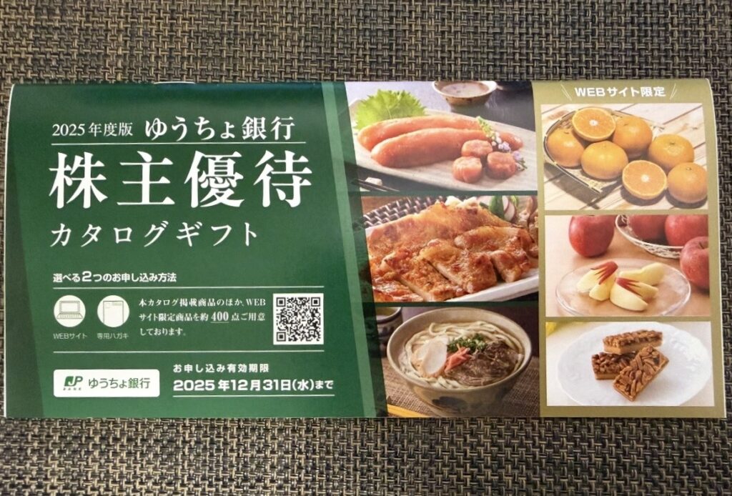 「2025年度版 ゆうちょ銀行 株主優待カタログギフト」の写真。
表紙には緑色のデザインで「ふるさと小包」のロゴが入り、
お肉・果物・うどん・スイーツなど全国の特産品が並んでいる。
WEB限定商品を含め約400点が選べる人気のカタログ優待。