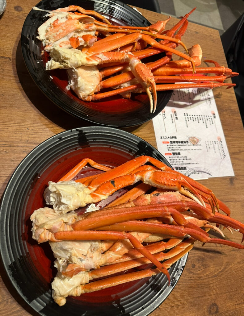 テーブルに並べられた本ズワイガニと紅ズワイガニの皿。食べ放題で提供された新鮮な蟹がたっぷり盛られている様子