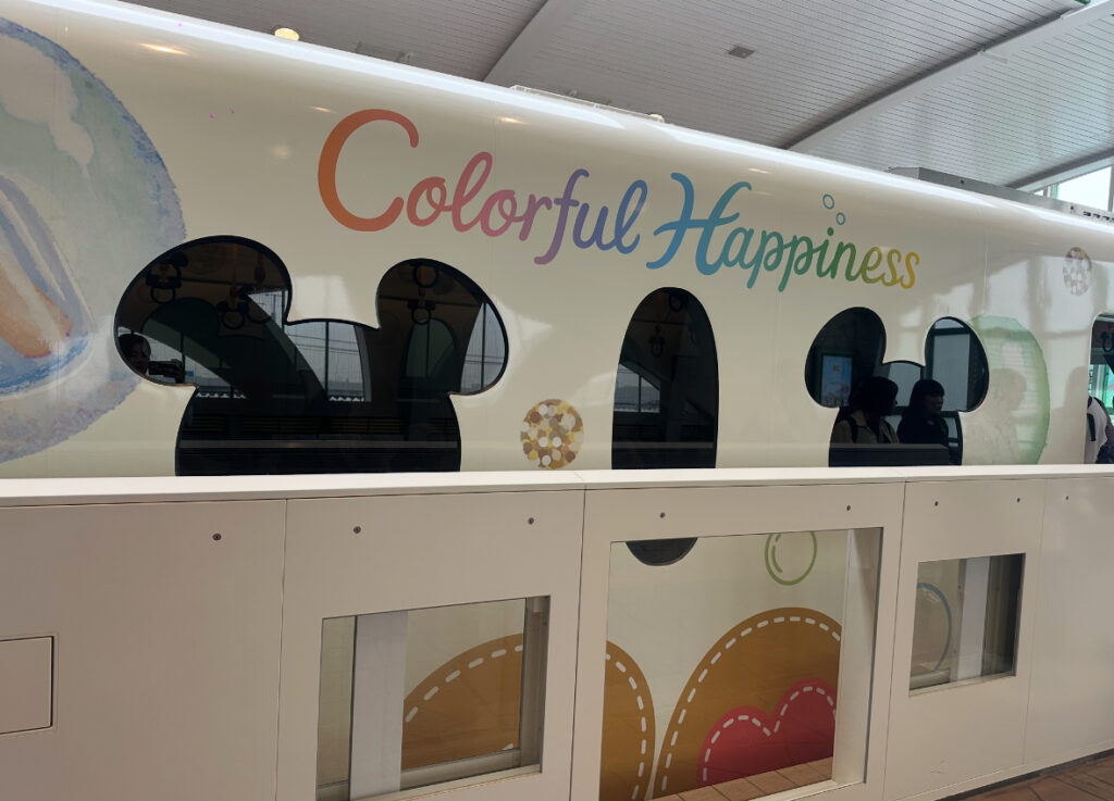 Colorful Happinessの文字が描かれた、ミッキー型の窓が特徴のディズニーリゾートラインの車両。