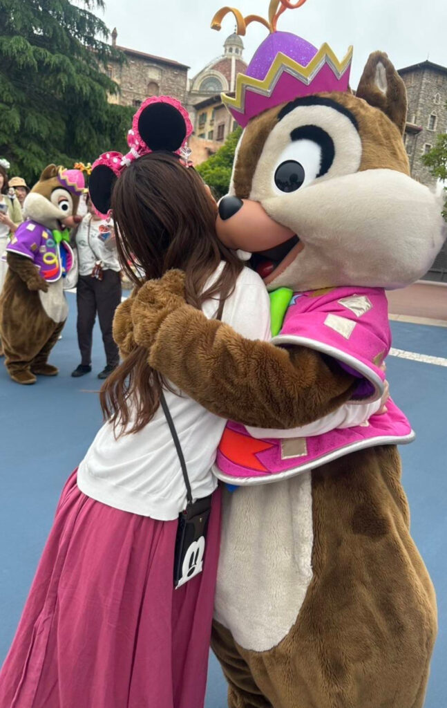東京ディズニーシーで、カラフルな衣装を着たチップと笑顔でハグする女性。再びふれあえるようになったグリーティングの象徴的な場面。