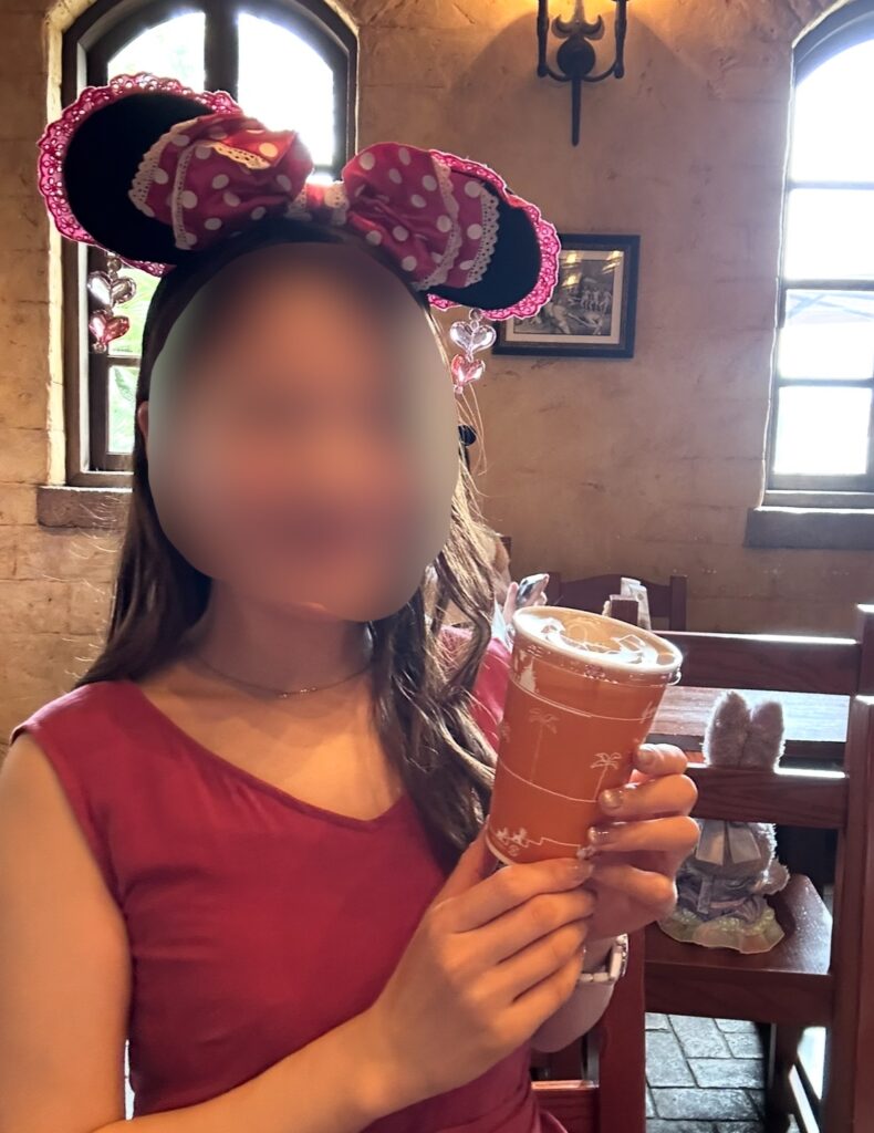 ディズニーシーのレストラン、ザンビーニ・ブラザーズ リストランテでアップルソーダを手にするブログ運営者COCO。りんごの爽やかな香りが広がる限定ドリンク。