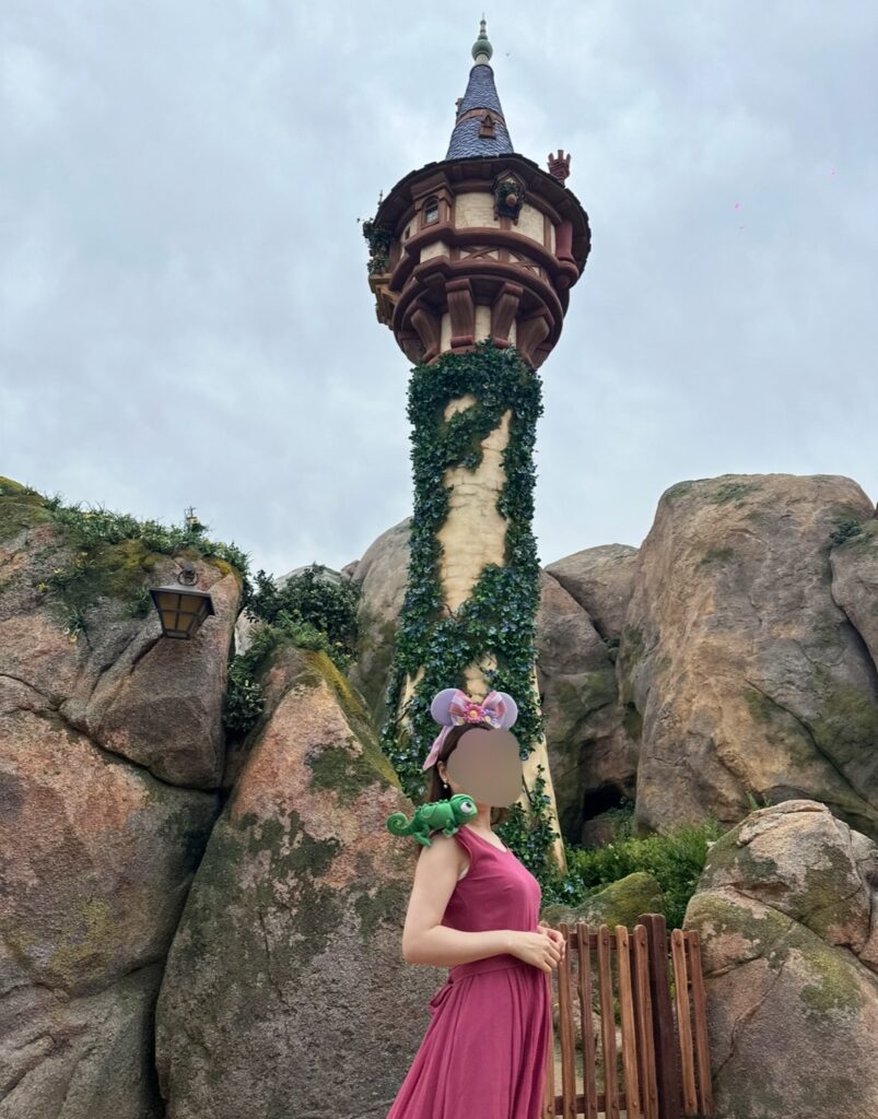 ファンタジースプリングスの人気スポット「ラプンツェルの塔」と一緒に写真を撮るブログ運営者COCO。映画『塔の上のラプンツェル』の世界観が再現されている。