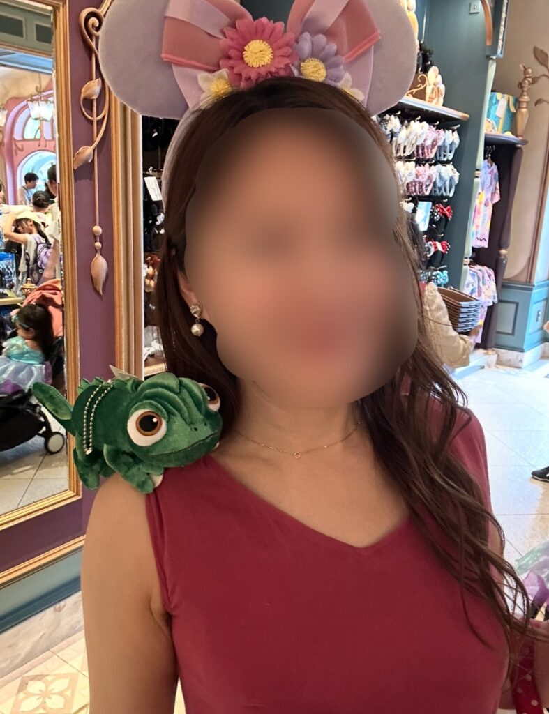 ファンタジースプリングスのお土産ショップで購入できる、カチューシャとラプンツェルの相棒・パスカルの肩乗せぬいぐるみをつけた様子。