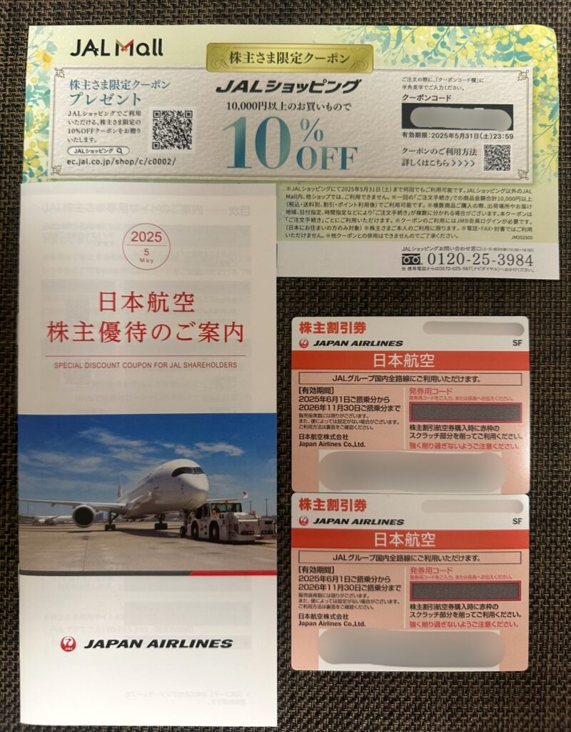 日本航空(JAL)の株主優待内容。JALショッピングで使える10%OFFクーポン、株主優待のご案内パンフレット、国内線株主割引券2枚が並べられている。