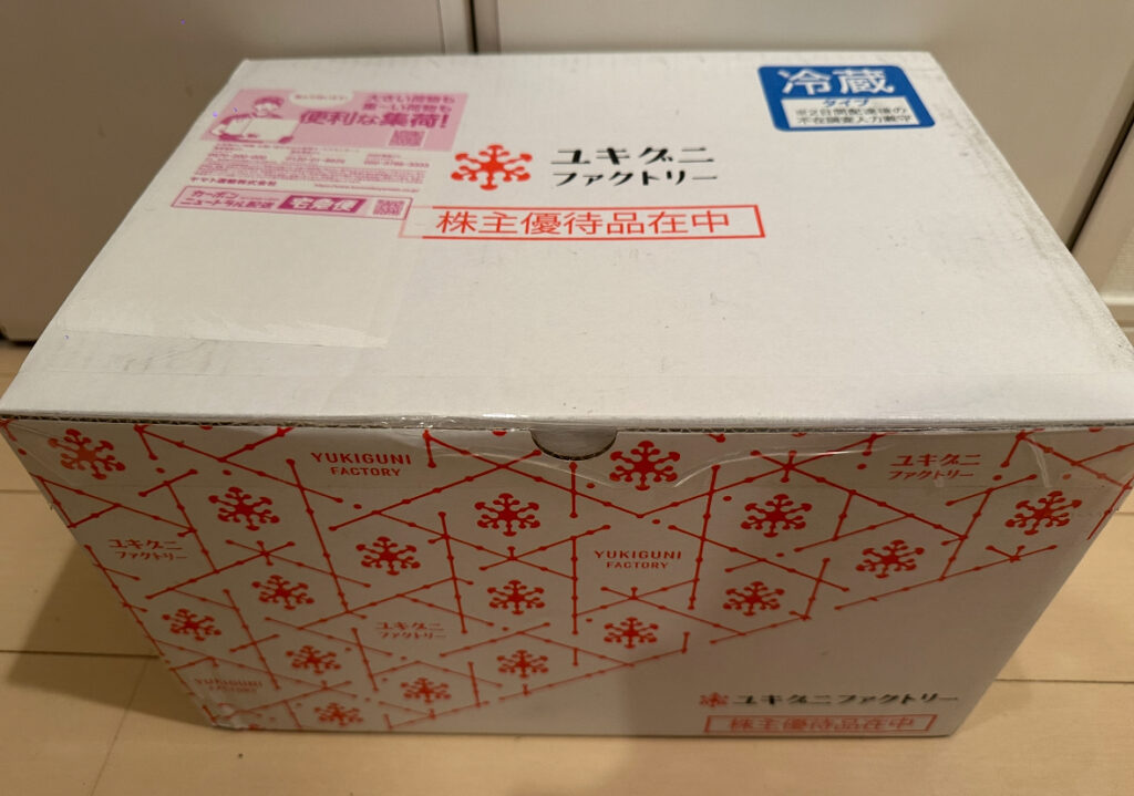 aユキグニファクトリーから届いた株主優待の外箱。段ボールには自社ロゴと注意書きが印刷されている。
