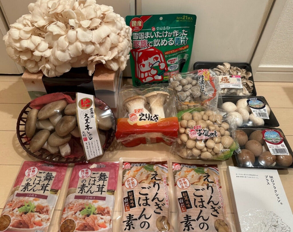 ユキグニファクトリーの株主優待で届いた、舞茸やエリンギ、ぶなしめじ、しいたけなどの国産きのこ詰め合わせと、炊き込みご飯の素や青汁パウチも並んだセット内容。Cセットの内容。