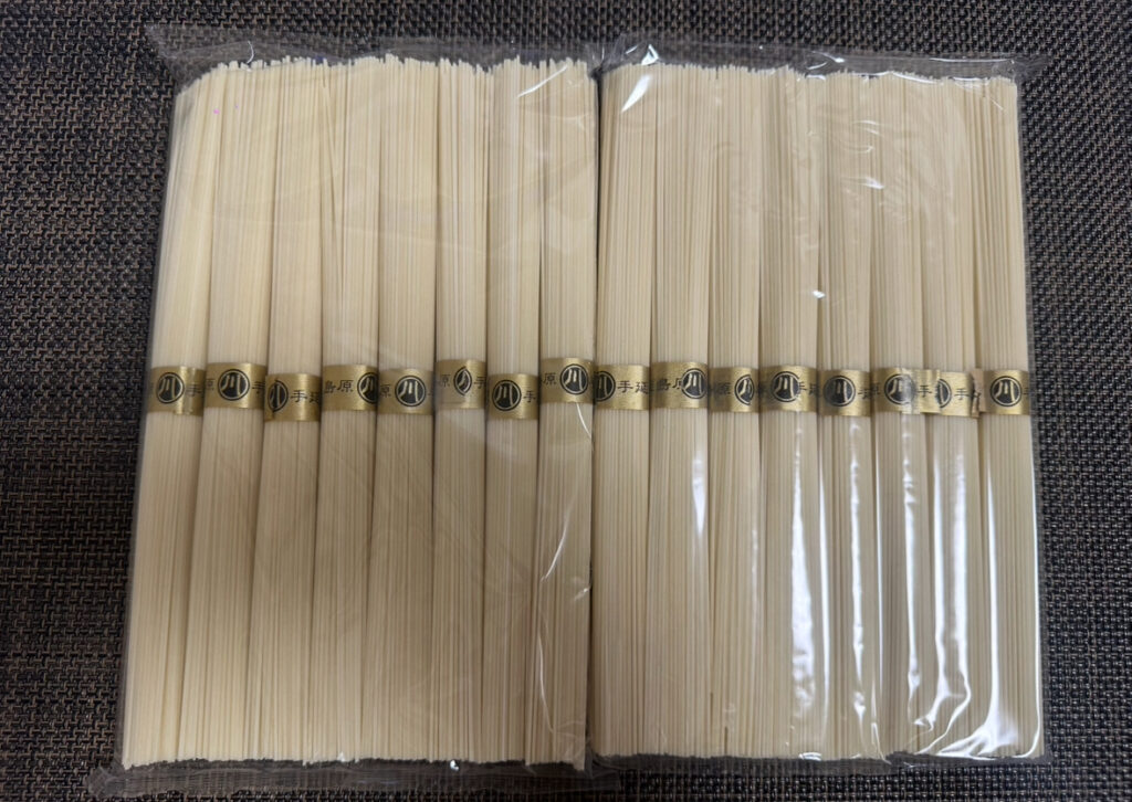 ビニール包装された島原手延べそうめんの束が並んだ様子。金の帯に「島原 手延べ素麺」と記載されており、高級感がある。