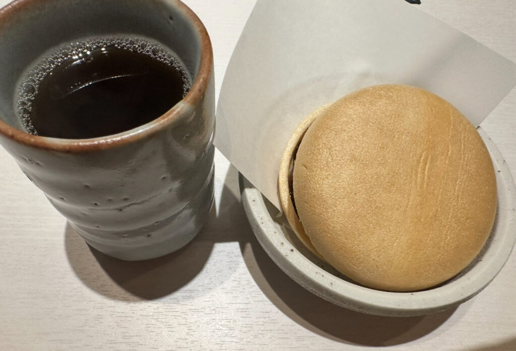 あんこがサンドされた丸い最中と、湯気の立つ温かいお茶がそれぞれ器に入れられて提供されている。