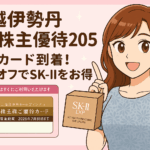 三越伊勢丹ホールディングス株主優待2025の記事用アイキャッチ画像。明るい茶髪のロング巻き髪で笑顔のブログ運営者COCOが、株主優待カードとSK-IIアイクリームを手に持ち、10％割引の特典を紹介しているイラスト。背景はピンクで可愛らしいデザイン。