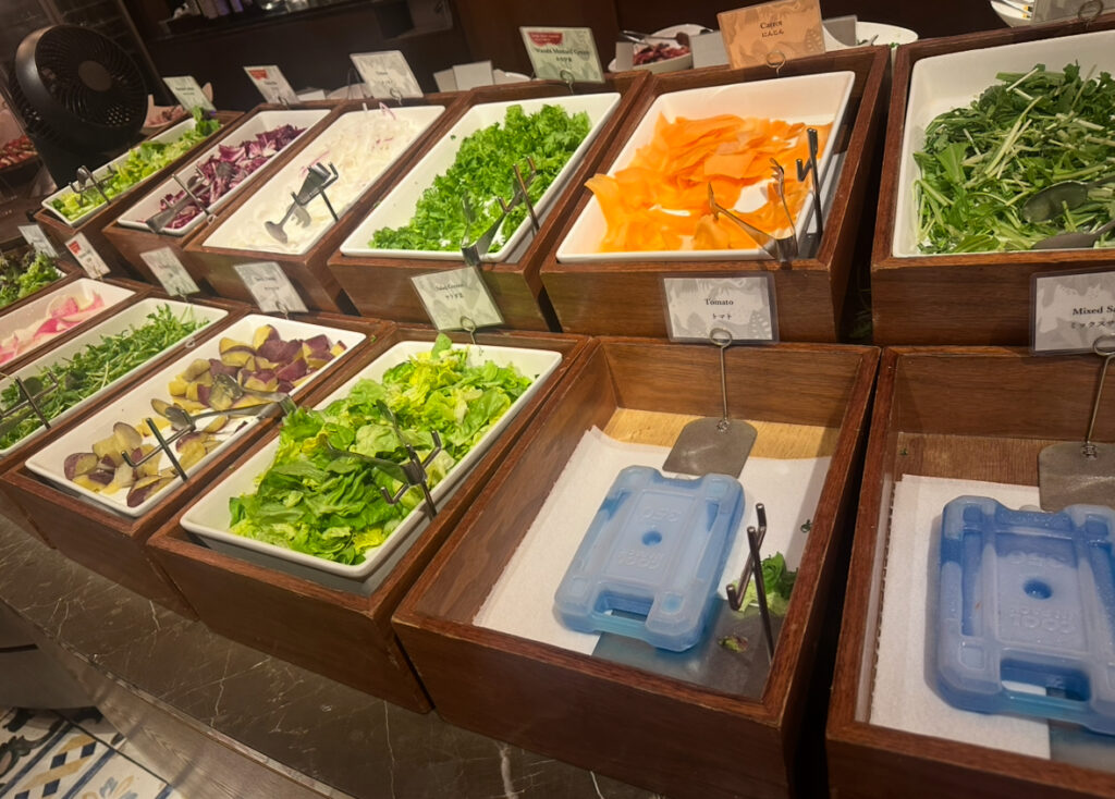 RIO GRANDE GRILL横浜ベイクォーター店のサラダバーに並ぶ新鮮な野菜。レタス、サツマイモ、トマト、紫キャベツ、水菜、オニオンスライスなど色とりどりの食材が並ぶ。