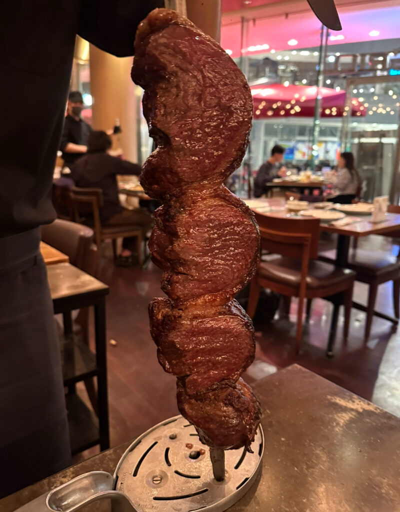 RIO GRANDE GRILL横浜ベイクォーター店のシュラスコ、ピッカーニャ（イチボ）。鉄串に刺さった肉厚の赤身肉が香ばしく焼き上げられている。