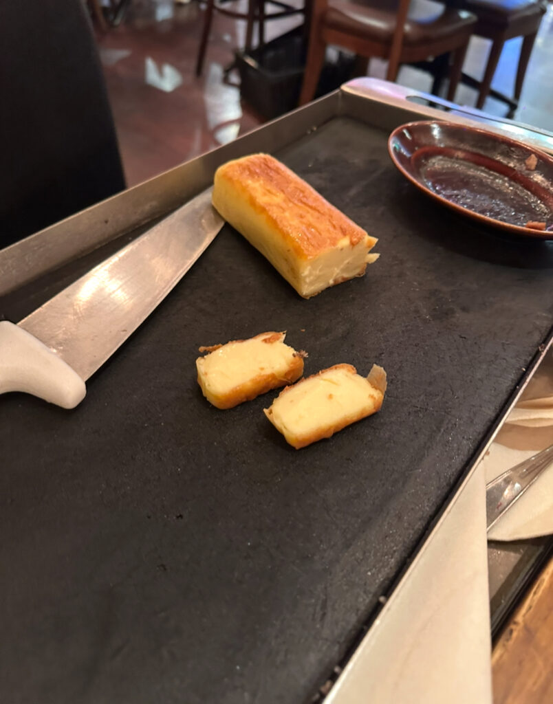 RIO GRANDE GRILL横浜ベイクォーター店のシュラスコ、焼きチーズ。鉄板の上でこんがり焼き色がついたチーズが香ばしく仕上がっている。