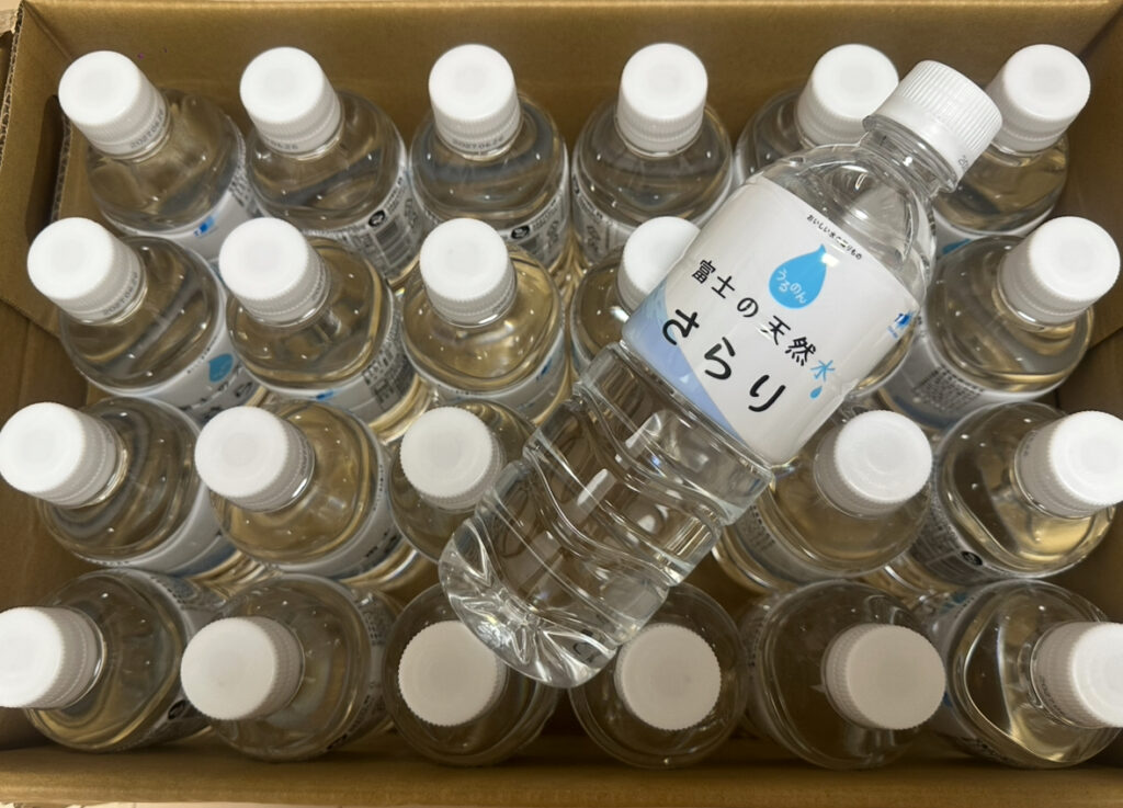 TOKAIホールディングスの株主優待Aコースで届いた「富士の天然水 さらり」500ml×24本（300株保有）を開封した様子。1本を手前に取り出し、透明なボトルと白いキャップが並ぶ様子が見える。