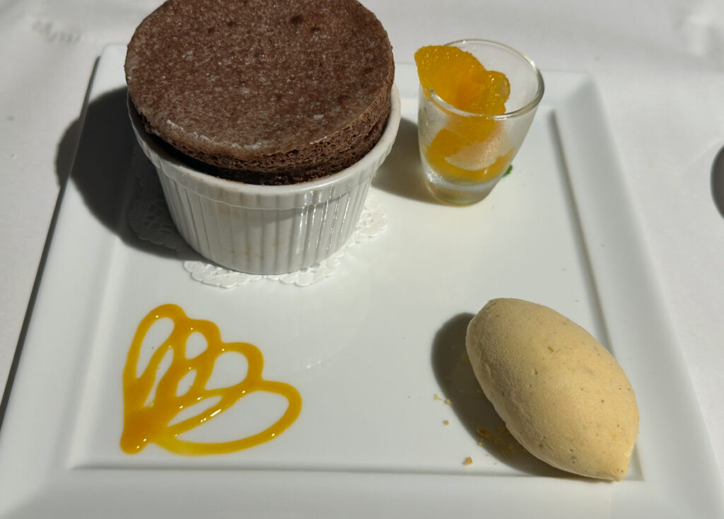 チョコレートスフレとオレンジのマセヒ、バニラアイスの3点盛りデザート。お皿には可愛らしいソースアートも添えられている。