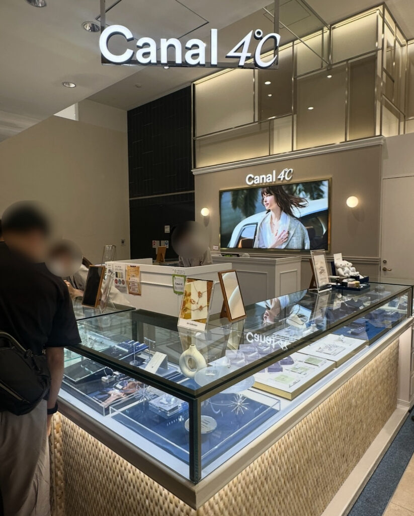 有楽町マルイのCanal 4℃店内の様子。ショーケースにジュエリーが美しく並び、奥には大型ディスプレイと明るい照明が映える上品な空間。