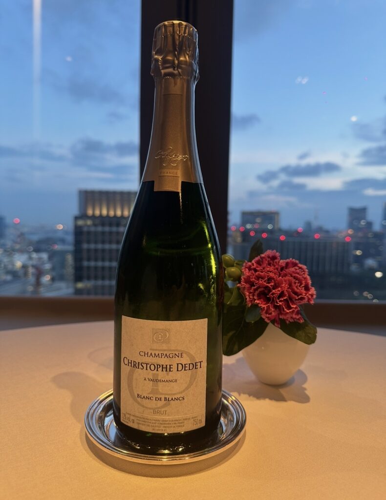 「CHAMPAGNE CHRISTOPHE DEDET(クリストフ・ドデ)」のブラン・ド・ブラン。丸ビル35階の窓際テーブルで夜景を背景に撮影された乾杯用シャンパンボトル。