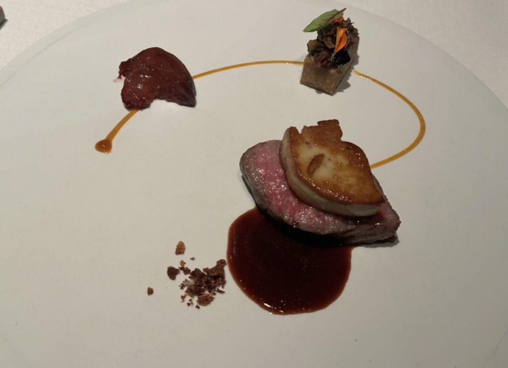 サンス・エ・サヴールのメイン料理「牛サーロインのロティ フォアグラのポワレ乗せ」。有料トッピングのフォアグラが加わり、赤ワインソースとパッションフルーツが華やかに調和する贅沢な一皿。