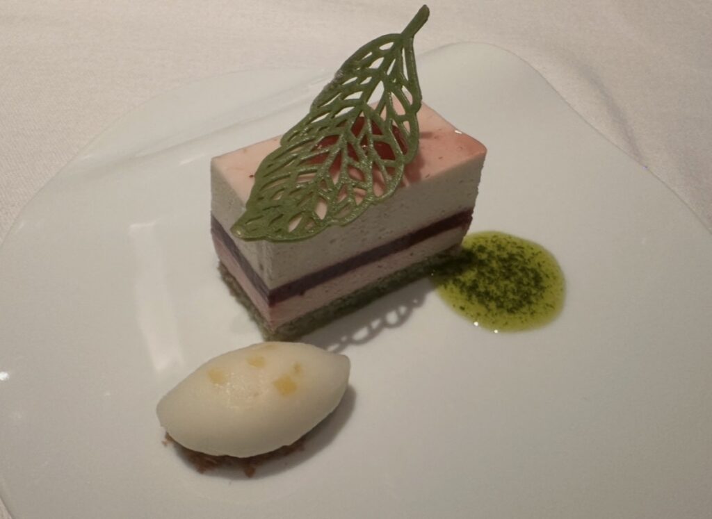 サンス・エ・サヴールのデザート。苺とピスタチオのムースケーキに繊細な葉形チョコが飾られ、横に柑橘のソルベとハーブソースが添えられた上品な一皿。