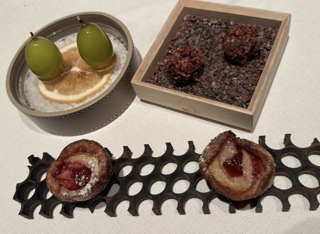 サンス・エ・サヴールのプティフール盛り合わせ。ぶどうのグラッセ、チョコレートトリュフ、いちごジャムを添えた焼き菓子など、ひと口サイズのデザートが美しく並べられている。