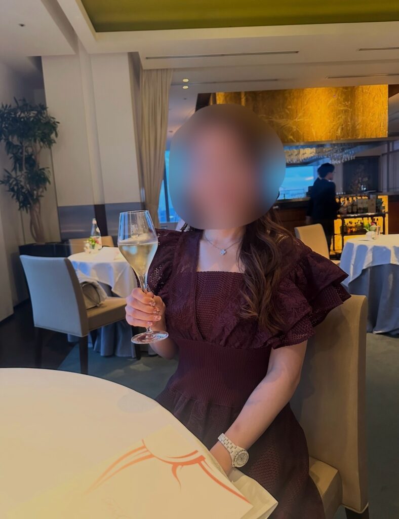 ブログ運営者COCOが丸の内ビル35階の「サンス・エ・サヴール」で乾杯している様子。誕生日ディナーで提供されたシャンパンを楽しむ瞬間。※顔はぼかしを入れて掲載しています。