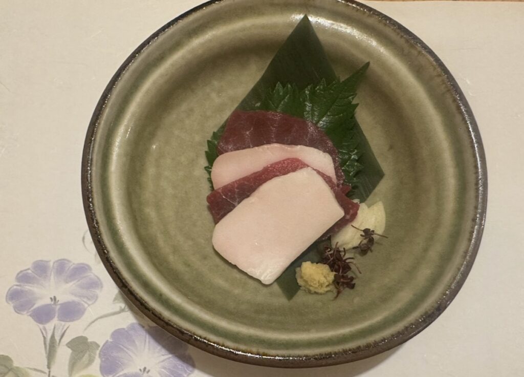 牛弁慶の刺身「馬刺しの紅白造り」。赤身とたてがみが重ねられ、大葉や薬味とともに美しく盛り付けられている。