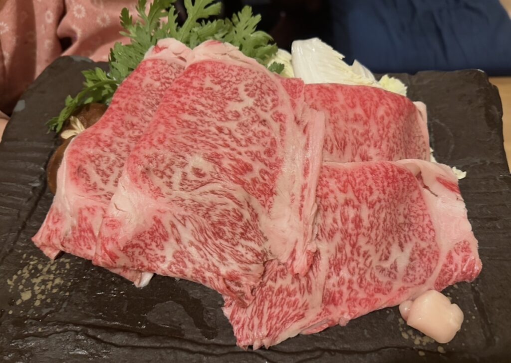 牛弁慶の牛鍋用「黒毛和牛サーロイン」。霜降りが美しい大判のサーロインが黒皿に盛り付けられている。