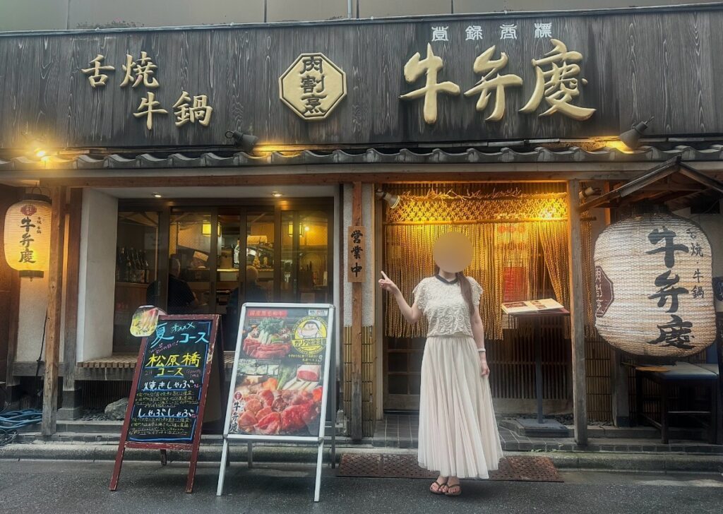 牛弁慶 新橋総本店の店頭に立つブログ運営者COCO。提灯や看板が並ぶ和風の外観とともに写る。※顔はぼかしを入れて掲載しています。