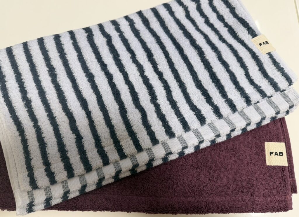 株主優待で実際に届いた今治タオルのフェイスタオルセット。ボーダー柄とボルドーカラーの2枚が並んでいる様子。