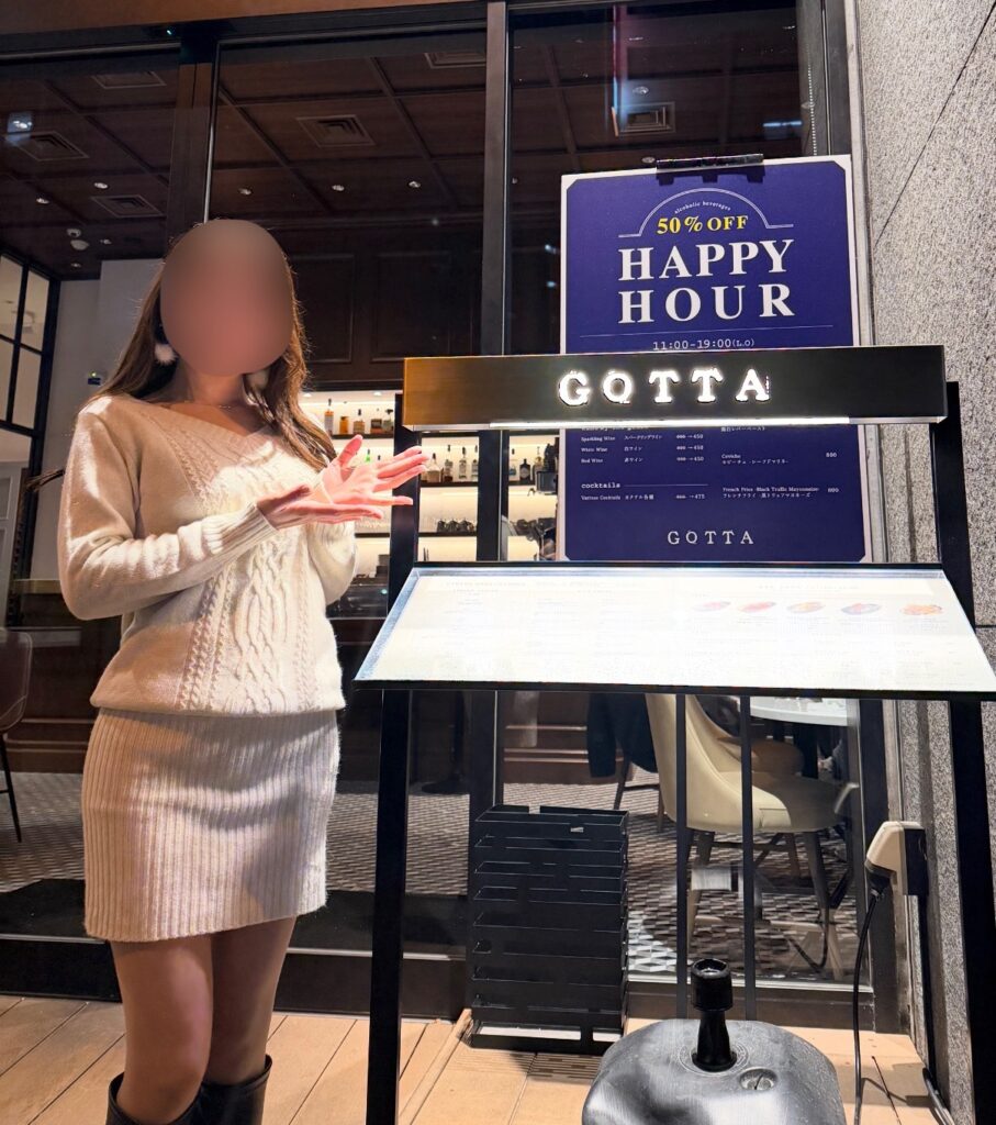 ブログ運営者COCOが五反田の「New American Dining GOTTA」店頭看板の前でポーズをとっている様子（※顔はぼかし加工をしています）