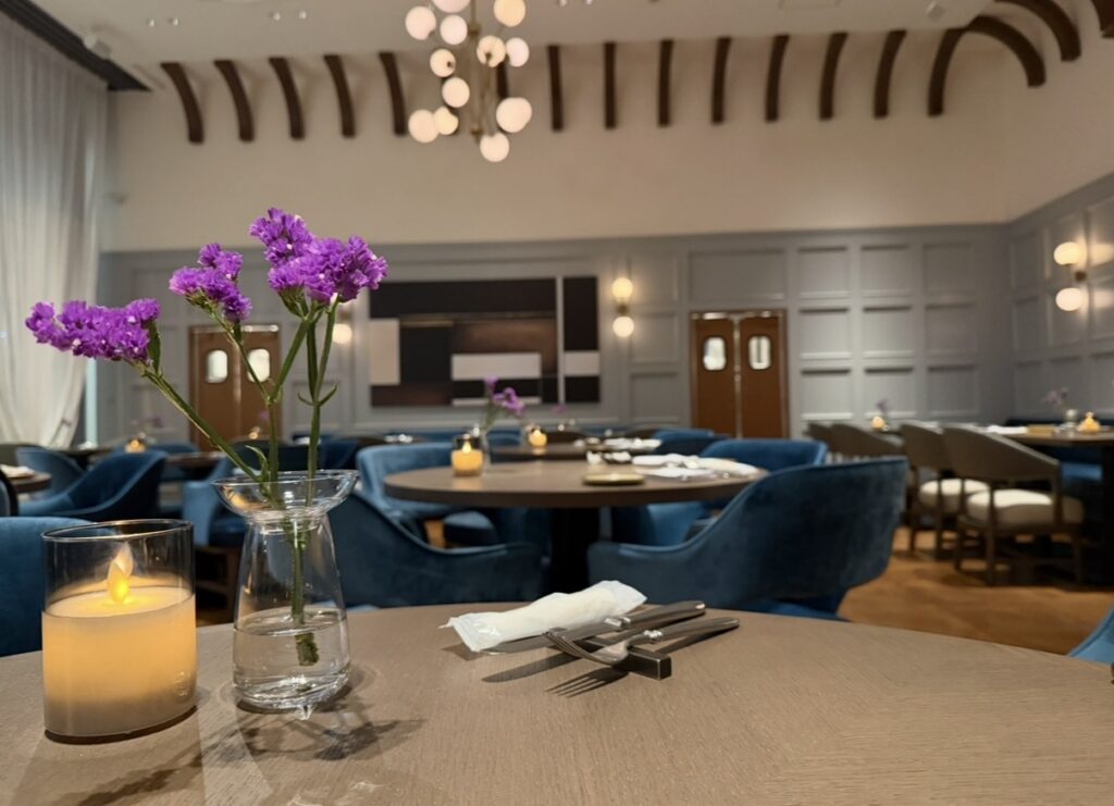 五反田「New American Dining GOTTA」の店内。テーブルの上に飾られた紫の花とキャンドル、落ち着いた照明とブルーのチェアが並ぶおしゃれで上質なダイニング空間。