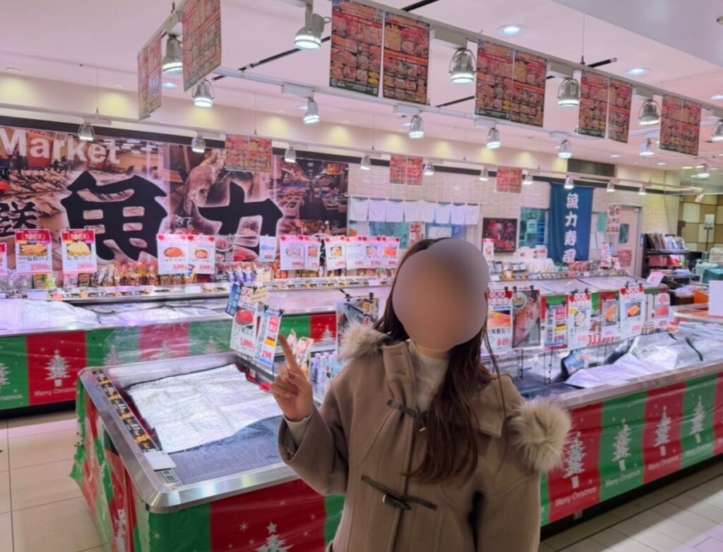 魚力の店内で買い物に来たブログ運営者COCOの写真（※顔はぼかし加工あり）。鮮魚コーナーや商品が並ぶ店内の様子が分かるイメージ写真