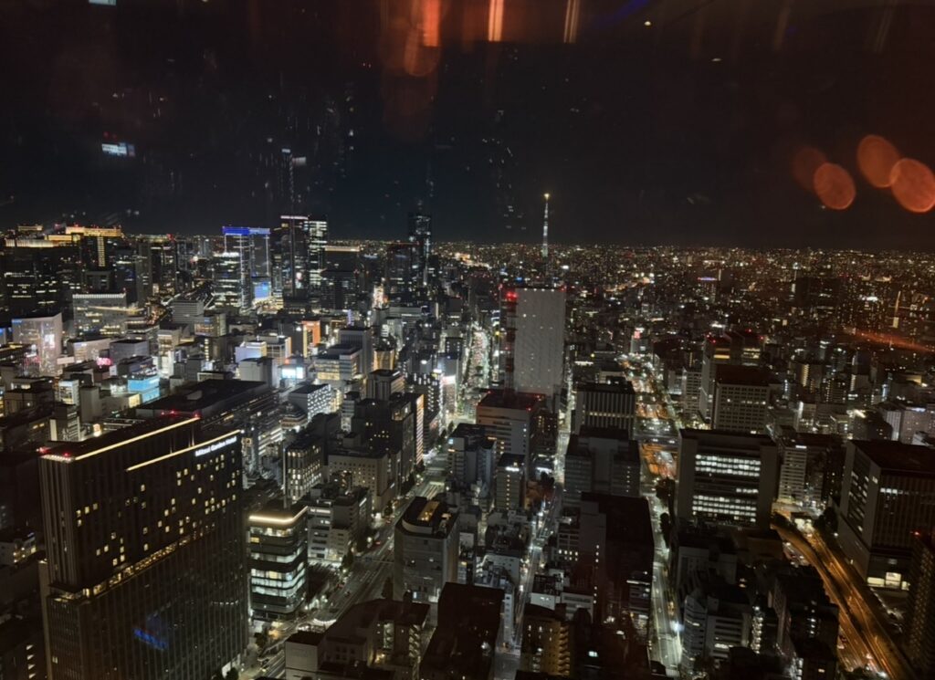 北の味紀行と地酒 北海道の高層階から見える東京の夜景。スカイツリーやビル群がライトアップされ、ディナー終盤には美しい夜景が広がっていた様子。