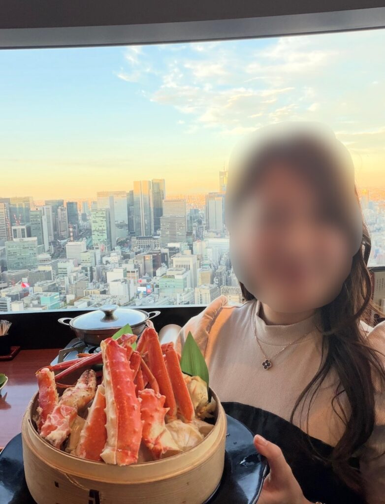 北の味紀行と地酒 北海道 カレッタ汐留店で、窓から見える絶景と一緒に蟹料理を楽しむブログ運営者COCOの様子(※顔はぼかし加工をしています)