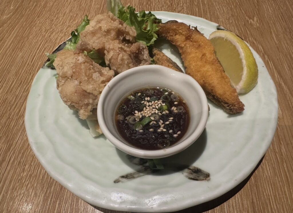 北海道名物ザンギとホッケの唐揚げ盛り合わせ。特製ポン酢だれとレモンが添えられた和皿の料理写真