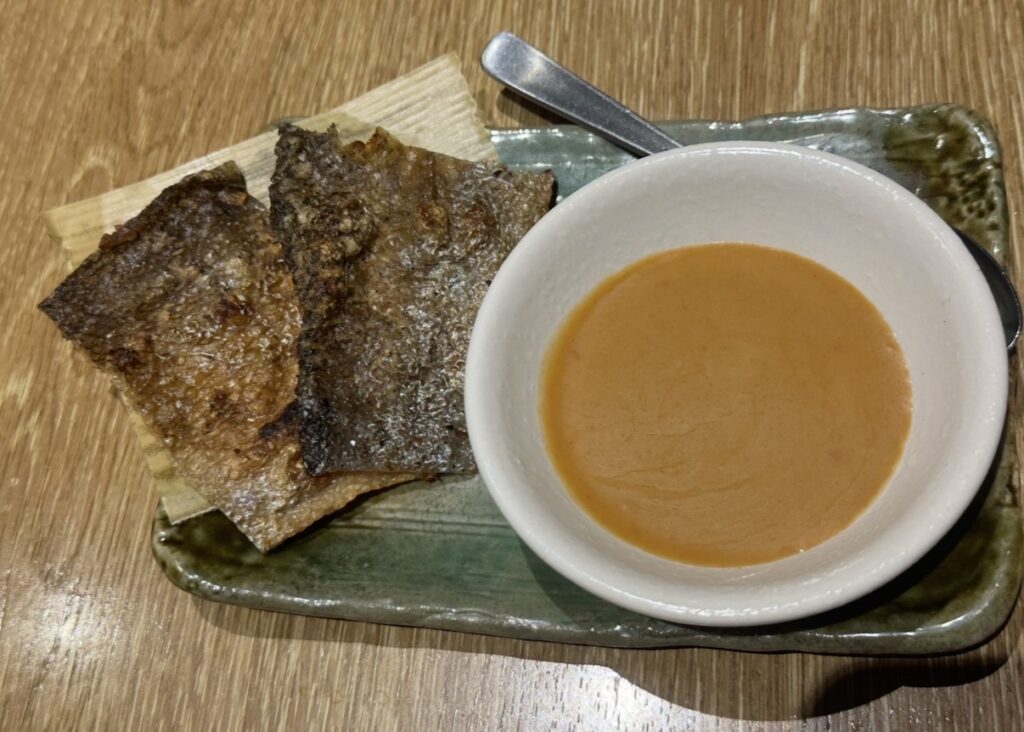 香ばしく焼き上げたスモーク鮭皮焼きと、味噌だれ風のソースが添えられた和皿の料理写真。