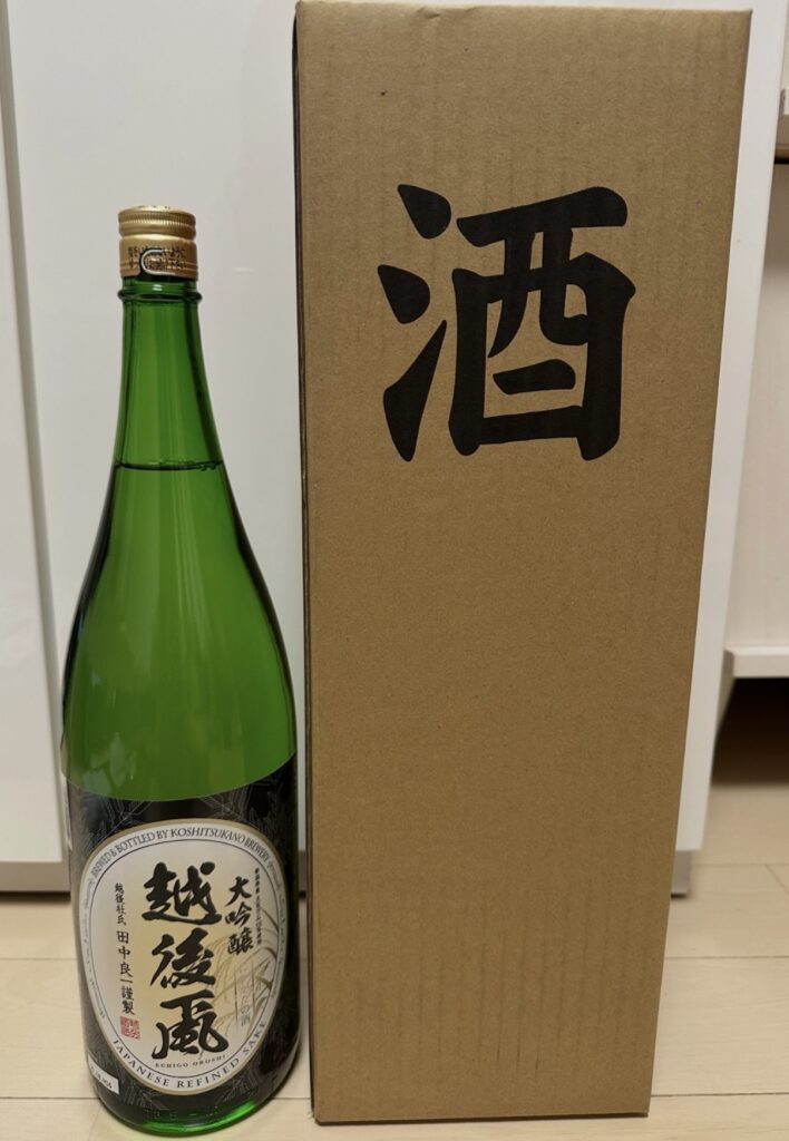 ベルーナ(9997)の2025年3月権利の株主優待で届いた「越後蔵 大吟醸」日本酒と、右側に立てかけられた「酒」と印字された専用の段ボール箱