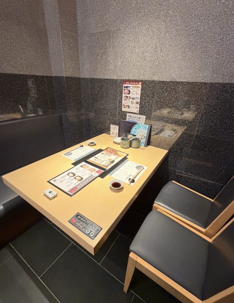 とらふぐ亭 目黒店の個室席の様子。テーブルにはコースメニューや調味料、注文用の案内が整えられており、落ち着いた雰囲気でふぐ料理を楽しめる空間。