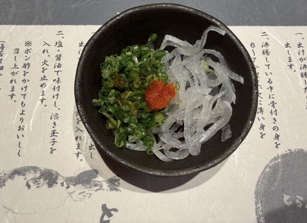 とらふぐ亭 目黒店の玄海コースで提供された、ふぐ皮刺し。細くカットされたふぐ皮に、刻みねぎともみじおろしが添えられた小鉢料理。