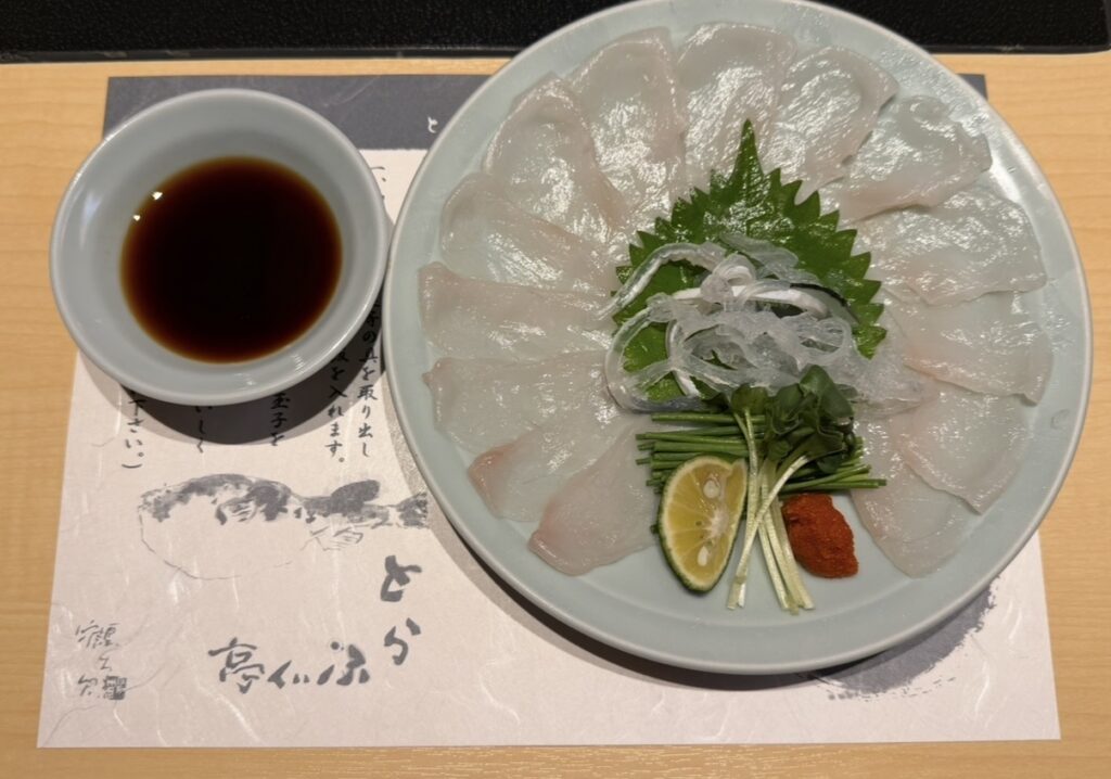 とらふぐ亭 目黒店の玄海コースで提供された泳ぎてっさ。薄く美しく並べられたふぐ刺しの中央に、刻みねぎ・もみじおろし・大葉・すだちが添えられ、ポン酢とともに提供される上品な一皿。