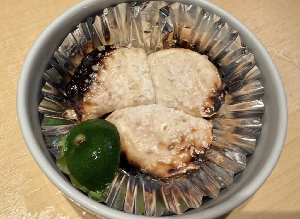 とらふぐ亭で提供された季節限定の焼き白子（塩）。香ばしく焼き目のついた白子が3つ、銀のカップに盛り付けられ、すだちが添えられた一皿。