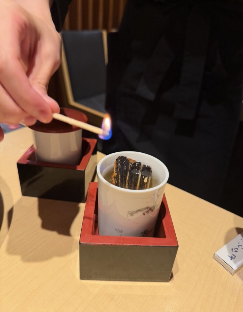 とらふぐ亭で提供されたひれ酒。マッチで火をつけ、香ばしい香りを立たせる仕上げの様子。白子と一緒に楽しむ大人の組み合わせ。
