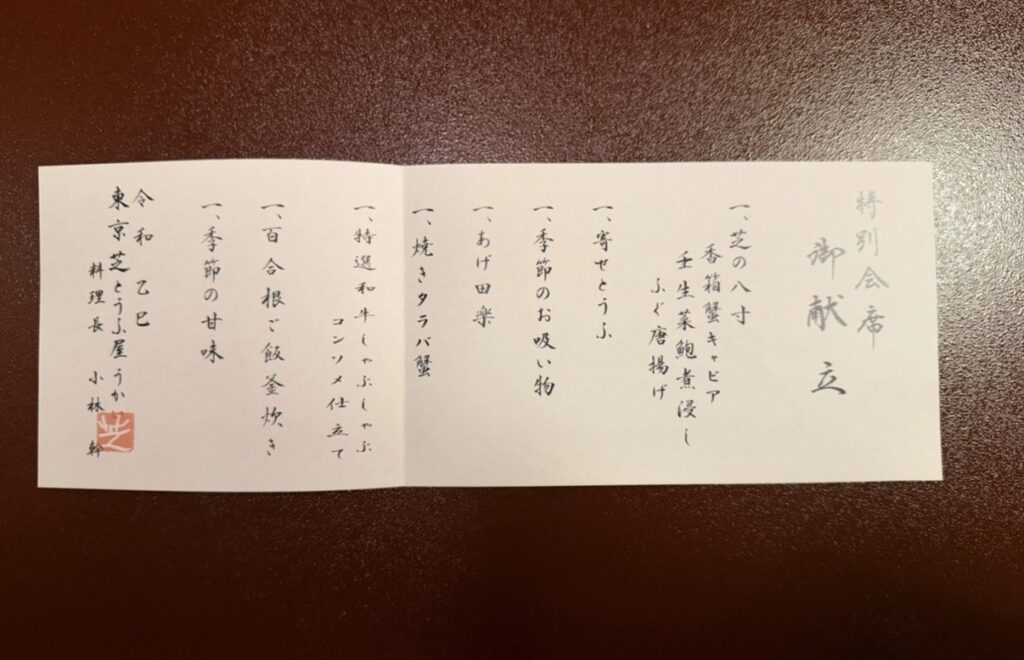 「とうふ屋うかいの特別会席メニュー表。芝の八寸、寄せとうふ、季節のお吸い物、焼きタラバ蟹、あげ田楽、特選和牛しゃぶしゃぶ、季節の甘味、百合根ご飯などの献立が並んでいる。」