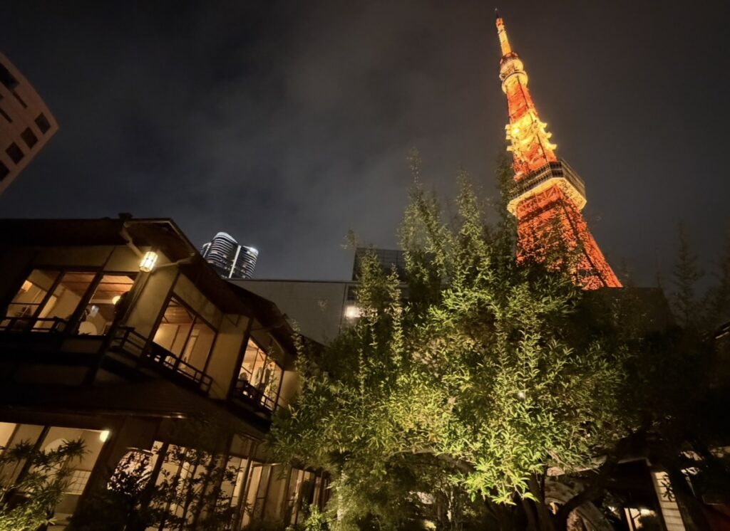 とうふ屋うかい芝店の個室が並ぶ建物越しに、ライトアップされた東京タワーがそびえ立つ夜景。柔らかく灯る部屋の明かりと、庭木のライトアップが重なり、和の静けさと東京らしい景色が同時に楽しめる一枚。