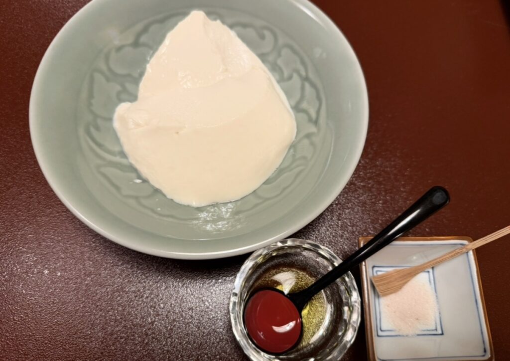 とうふ屋うかい芝店の名物・寄せとうふ。器に盛られた寄せとうふと、オリーブオイル、塩が添えられ、シンプルな食べ方で素材の味を楽しむ様子。