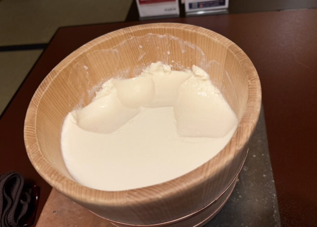 とうふ屋うかい芝店の名物・寄せとうふ。木桶の中にたっぷり入った寄せとうふはおかわり可能で、なめらかな豆腐と豆乳が楽しめる。