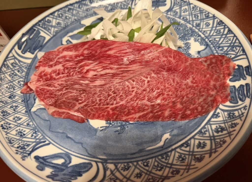 特選和牛しゃぶしゃぶ（コンソメ仕立て）｜美しいサシの入った和牛と白髪ねぎを盛り付けた一皿。