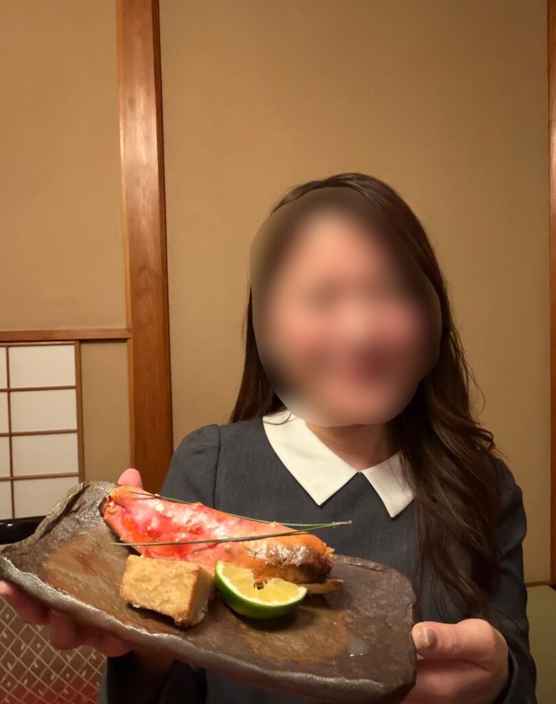 特別会席の焼きタラバ蟹を手に持つブログ運営者COCO ※顔はぼかしを入れて掲載しています。