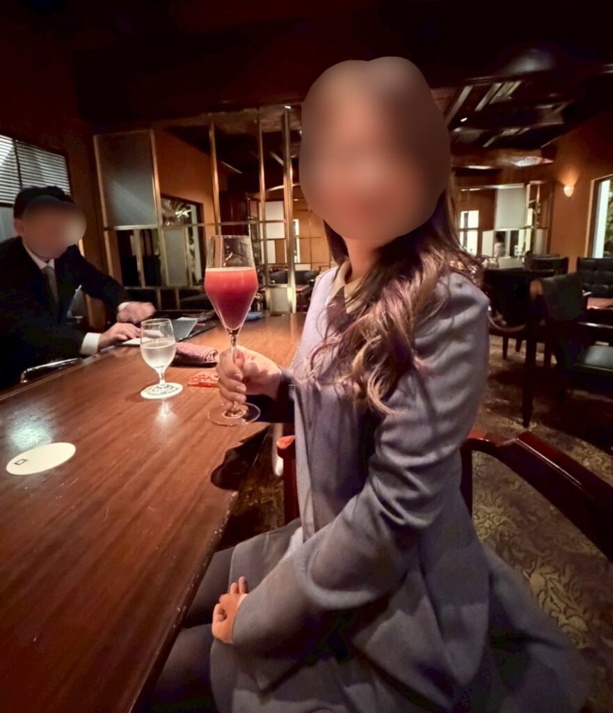 吉祥庵でいただいた季節のフルーツを使った葡萄のシャンパンカクテル。カウンターに置かれたグラスと、奥に並ぶボトルが大人の雰囲気を演出している。