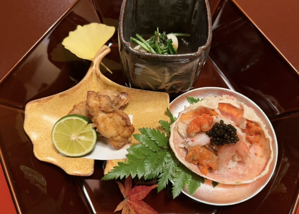 とうふ屋うかい芝店の特別会席で提供された芝の八寸。蟹やいくらを使った小鉢や季節の揚げ物が美しく盛り付けられ、秋の葉が添えられた華やかな前菜の盛り合わせのアップ写真。