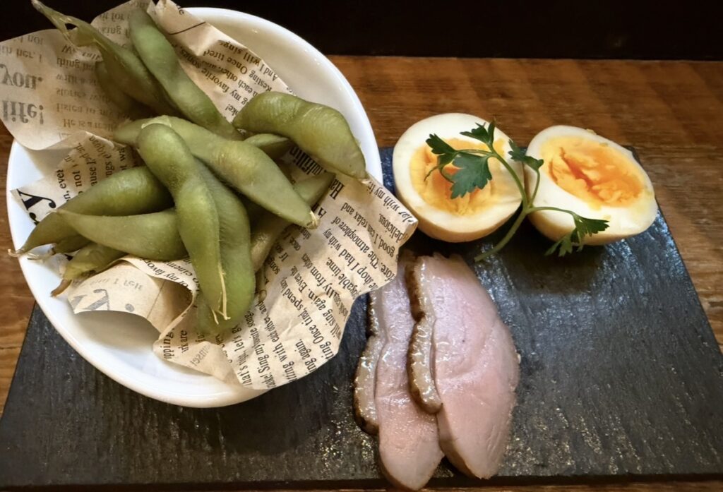 大崎キッチン（OSAKI KITCHEN）のデラックスコースで提供された「自家製燻製3種盛り合わせ」。合鴨、半熟玉子、枝豆を燻製にした盛り合わせで、スモークの香りがしっかり感じられる一皿。